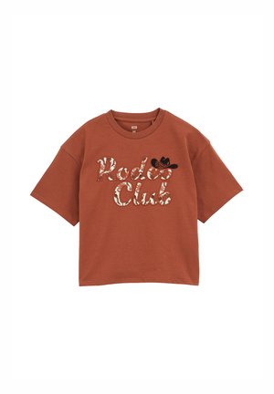 T-shirt oversize marrone con maniche corte, con la scritta "Rodeo Club" ricamata in un font da cowboy e un piccolo accento di cappello da cowboy nero.
