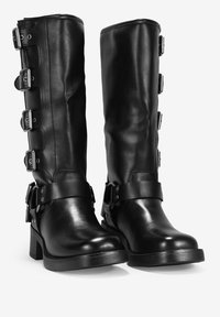 Botas de cuero negras hasta la rodilla con punta redondeada, que presentan múltiples hebillas y correas metálicas a lo largo del costado para un detalle adicional.