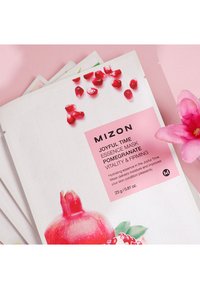 MIZON Joyful Time Essence Mask-förpackningen har en vit bakgrund med illustrationer av granatäpplen, rosa detaljer och text som beskriver produktens fördelar.