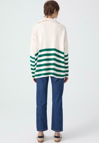 Gehaakt sweater met witte en groene strepen, met kraagontwerp, gecombineerd met blauwe rechte spijkerbroek en platform schoenen.