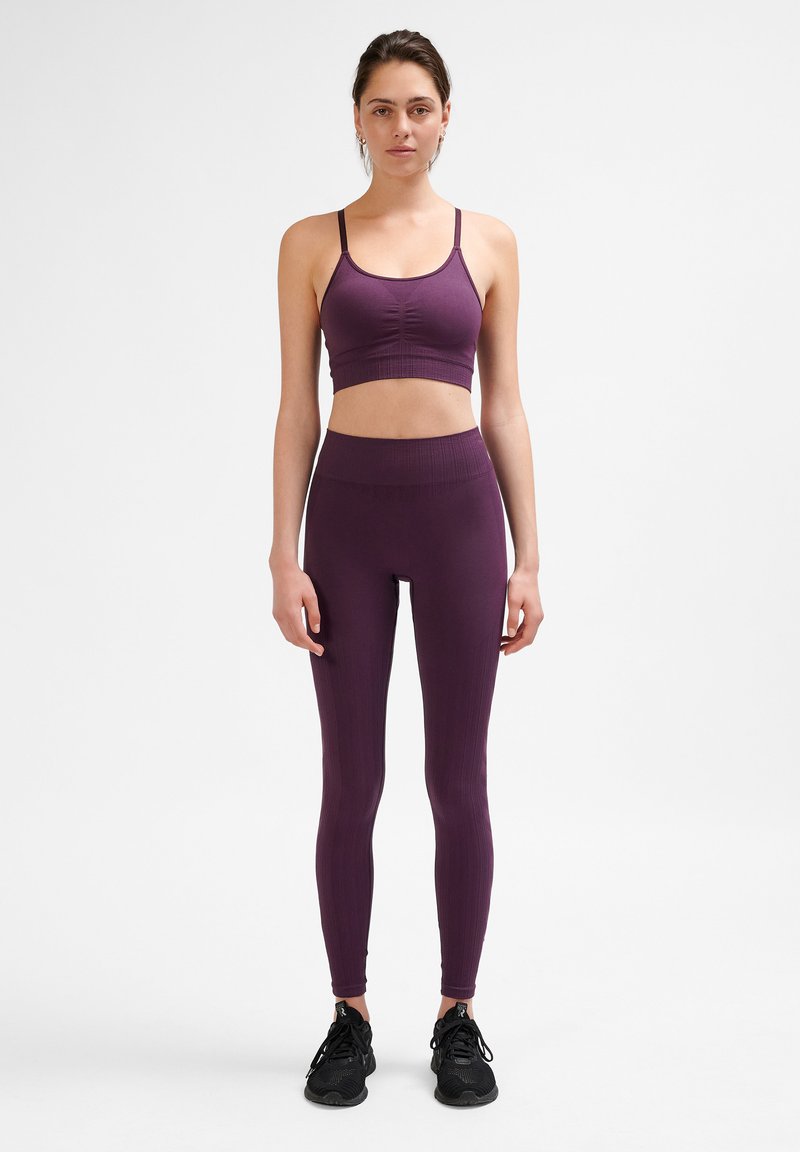 Lila ribbad sport-bh och leggings-set med en åtsittande design. Materialet är stretchigt; har tunna axelremmar och ett högt midjeband för stöd.