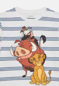 Camisa blanca de manga corta con rayas azules que presenta personajes de dibujos animados: un jabalí, un león y una suricata en colores vibrantes.