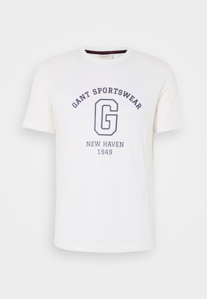 Fehér pamut póló, kerek nyakkivágással, rövid ujjakkal és sötétkék nyomtatott szöveggel: "GANT SPORTSWEAR", "NEW HAVEN" és "1949".