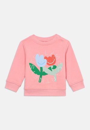 Sweat-shirt en coton rose avec un motif floral comprenant des fleurs souriantes en bleu et rouge, des feuilles vertes, et un texte contrastant en blanc. Manches longues.