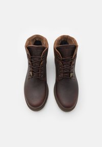 Botas de tobillo de cuero marrón con diseño de cordones, parte superior texturizada y collar acolchado. Suela de goma y detalle del logotipo en el lateral.