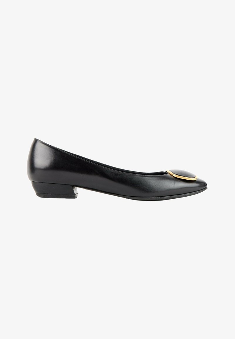 Ballerine noire en cuir à petit talon, avec un bout rond et un ornement circulaire bordé d’or sur le dessus.