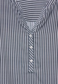 Camicia button-up a righe con scollatura a V, caratterizzata da righe verticali blu navy e bianche, tessuto leggero e cinque bottoni.