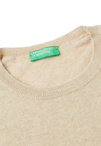 Beige trui gemaakt van een zachte stof, met een ronde halslijn, ribgebreide randen en een groene label met de tekst "United Colors of Benetton."