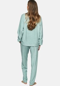 Ensemble de pyjama en polaire de couleur bleu clair, comprenant un haut à manches longues avec un ourlet arrondi et un pantalon ample avec une taille élastique.