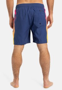 Costume de baie bleu marin cu un brâu elastic, având dungi colorate pe laterale în roz, portocaliu și galben, și un buzunar la spate cu un buton.