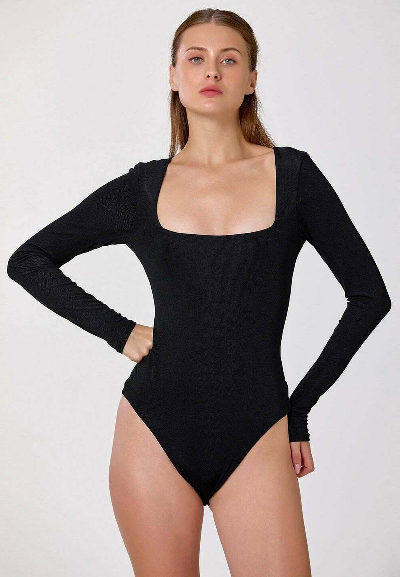 Body noir à manches longues avec décolleté carré, fabriqué en tissu côtelé. Présente des jambes à échancrure haute et une silhouette ajustée pour un look épuré.