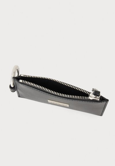 Zwart rechthoekig leren etui met zilveren rits en grote zilveren ring bevestigd aan één uiteinde.