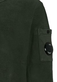 Giacca in pile verde con finitura testurizzata, tasca a toppa sulla manica e un accento a forma di logo circolare.