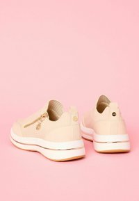 Beige slip-on cipők textúrált anyagból. Oldalsó cipzárral rendelkezik, arany kiegészítőkkel, fehér középtalppal és világosbarna talppal.