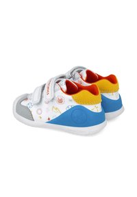 Scarpe bianche per bambini con motivi giocosi multicolori, accenti grigi, suole blu e doppie fascette in Velcro per una facile vestibilità.