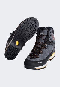 Graue Wanderschuhe aus synthetischem Material mit einer dicken schwarzen Sohle, orangefarbigen Akzenten, robustem Profil und verstärkter Zehenkappe.
