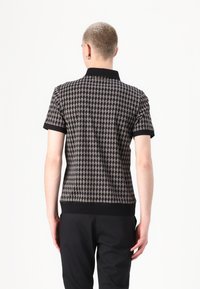 Lühikeste varrukatega polo särk, millel on šakali muster, must kaelus ja varrukaotsad, sobiva disainiga ja sile tekstuur.