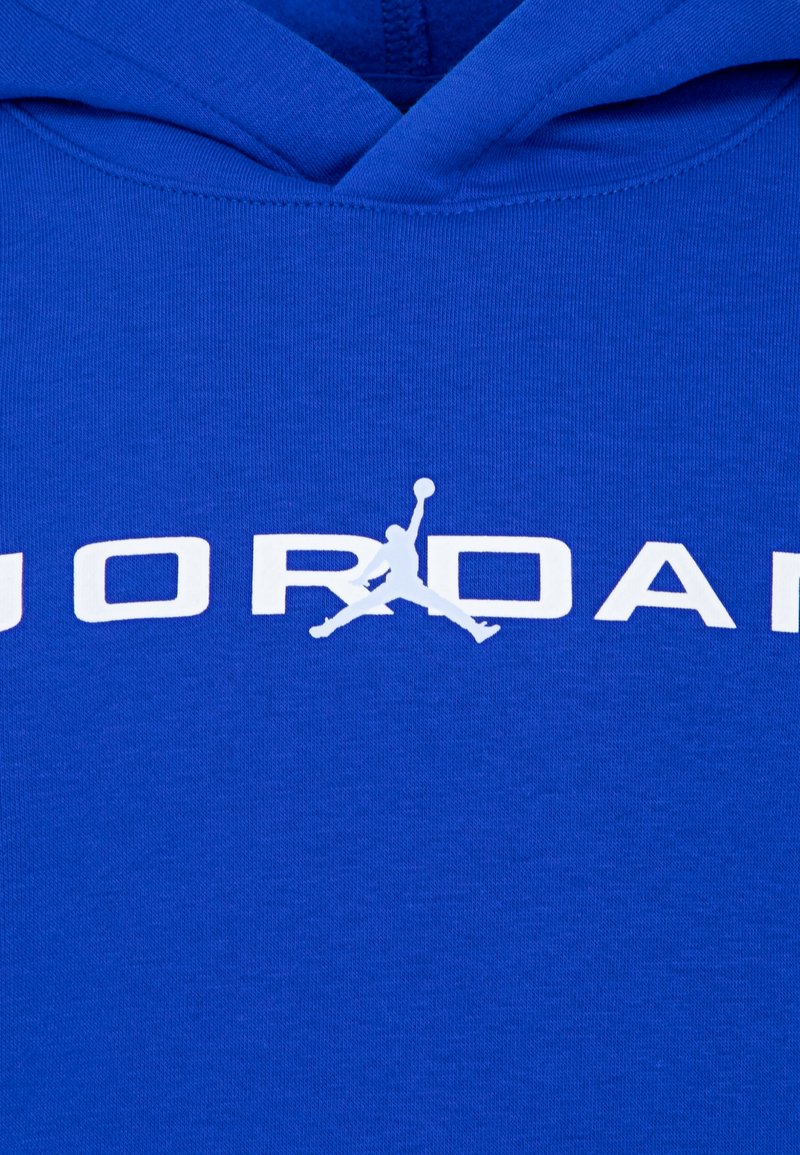 Sweatshirt à capuche bleu avec un grand texte blanc "JORDAN" et un emblème représentant une figure en train de sauter, fabriqué en tissu lisse.