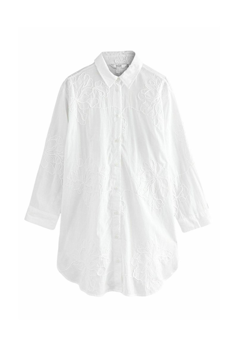 Chemise blanche à boutons, fabriquée en tissu texturé, avec une broderie florale sur le devant et des manches longues avec des poignets à button.