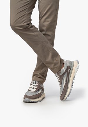 Zapatillas deportivas grises con una mezcla de ante y malla, que cuentan con una suela gruesa, cordones blancos y acentos estampados en un beige claro.
