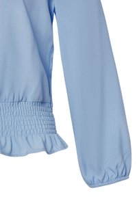 Blusa azzurro chiaro con maniche lunghe, vita arricciata e polsini con volant. Tessuto morbido con un design fluido e una caduta delicata.