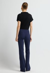 Svart kortärmad topp och marinblå välpassande byxor. Slätt tyg med klassisk skärning. Byxorna har hög midja och rak bendesign.