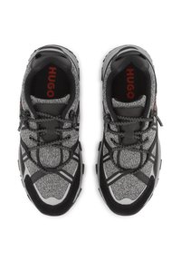 Chaussures de sport noires et grises avec une tige en tissu texturé, des accents réfléchissants et une semelle en caoutchouc, dotées d'un système de laçage sécurisé.