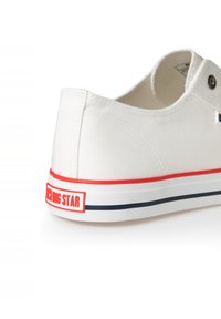 Weiße Leinensneaker mit einer rot-blauen gestreiften Sohle, einem Logotag und einem abgerundeten Design mit minimalen Akzenten.