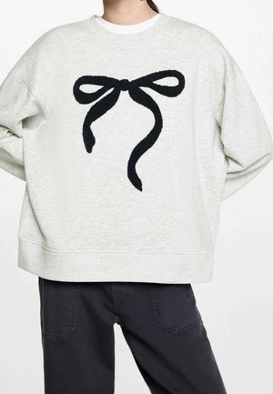 Jasnoszara bluza z dużym czarnym wzorem kokardy na przodzie. Posiada okrągły dekolt i szeroki, luźny krój. Miękka tekstura materiału.