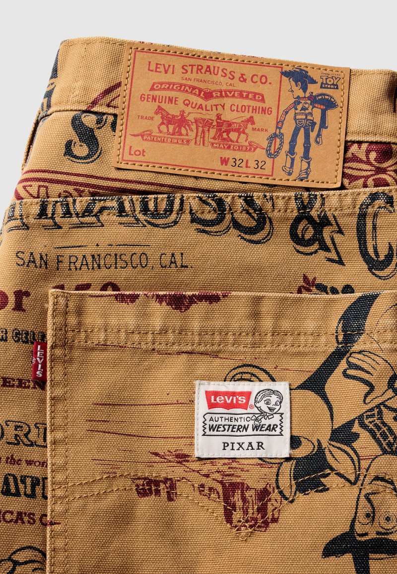 Levi's denim med en tan bas, prydd med röda och svarta tryckta grafik och en brun läderetikett. Inkluderar en vit tagg med "Pixar"-logotyp.