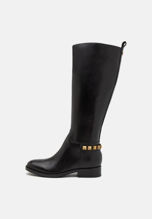 Botte en cuir noire montant au genou, avec un bout arrondi, un petit talon carré et des clous métalliques dorés le long de la cheville. Texture lisse avec un design ajusté.