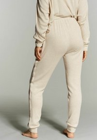 Beige joggerbroeken van zachte stof, met een elastische tailleband, taps toelopende benen en zijzakken met contrasterende stiksels.