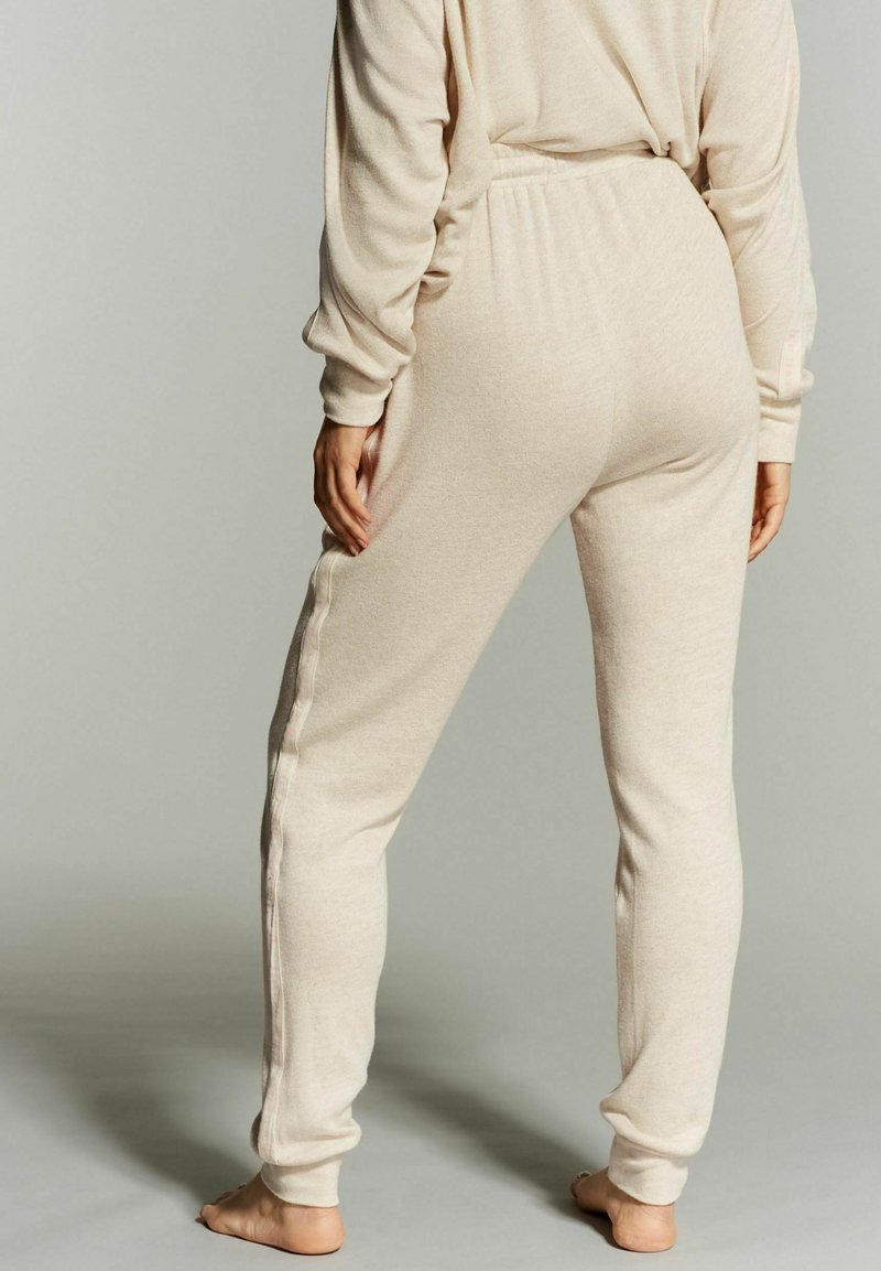 Beige joggerbroeken van zachte stof, met een elastische tailleband, taps toelopende benen en zijzakken met contrasterende stiksels.