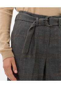 Graue karierte hochTaillenhose mit braunen Akzenten und einem Gürtel mit einer runden Metallschnalle. Strukturierter Stoff mit Falten.