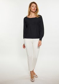 Top negru cu mânecă lungă, cu o guler larg, asortat cu pantaloni albi slim-fit și pantofi deschiși, cu accente de fundiță. Design simplu și clasic.