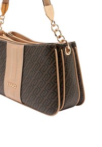 Brun mønstret håndtaske med beige læderdetaljer; har en kædetaske og lynlåslukning; dimensioner velegnede til daglig brug.