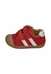 Red leather shoe with two white stripes, rounded toe, and two adjustable Velcro straps. Features a tan rubber sole and stitched accents.