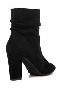 Black suede ankle boots with a high, chunky heel and folded upper design. Smooth texture with a streamlined shape and no visible hardware.