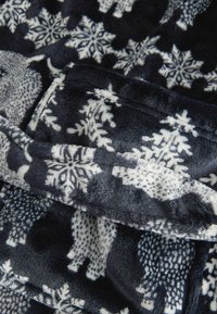 Pătură din fleece cu un fundal albastru închis și modele de fulgi de zăpadă și urși, textură moale și margini pliate.