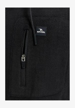 Schwarze Fleecejacke mit einer Reißverschlusstasche auf der Brust, strukturiertem Stoff und einem kleinen schwarz-weißen Logo-Patch.