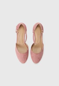 Escarpins en daim rose à talons hauts avec un dos ouvert, une sangle avec une boucle en or et une conception de bout lisse et arrondi.