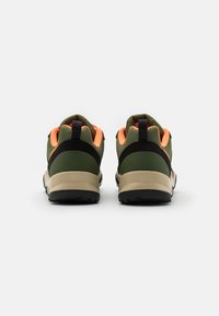 Scarpe da trekking verdi e nere con accenti arancioni. Presentano una superficie testurizzata e una suola spessa e robusta. Include un anello di tiraggio sul retro.
