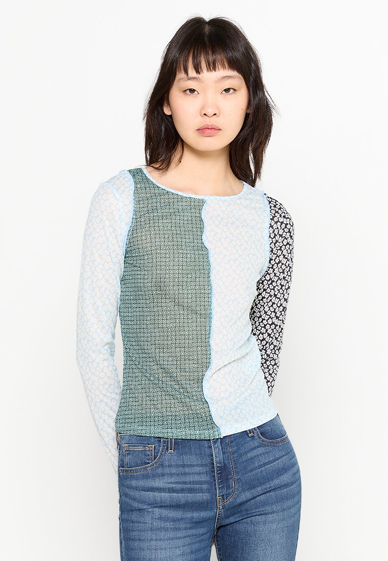 Top de manga larga con cuatro patrones distintos: azul claro, verde y negro, con diseños florales y geométricos. Textura suave, estilo ajustado.