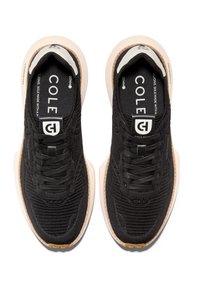 Černé pletené tenisky s texturovaným povrchem, s kontrastní béžovou podrážkou, černými tkaničkami a logem na jazyku.