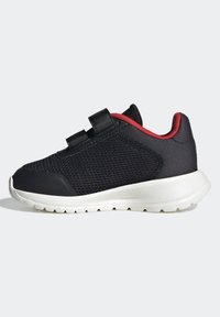 Černá sportovní bota s síťovinou, bílou gumovou podrážkou, červenými detaily na patě a dvojicí suchých zipů pro bezpečné zavření.