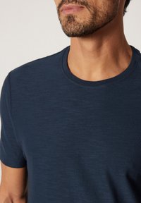 Marinblå crew-neck t-shirt i mjuk väv med en lätt struktur. Korta ärmar, åtsittande mot kroppen och en ren, enkel design.