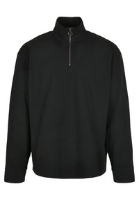 Zwarte pullover met hoge kraag en halve ritssluiting. Heeft lange mouwen en een ontspannen pasvorm. De stof lijkt zacht en glad te zijn.