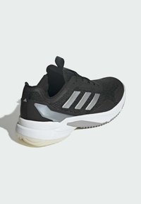 Zwart sportschoen met een bovenwerk van mesh, drie zilveren strepen, een wit, gevoerd middenzool en een grijze buitenzool. Voorzien van een lus aan de hiel.