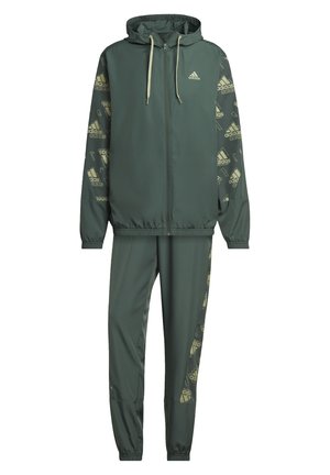 Groen Adidas trainingspak met een capuchon en ritssluiting op het jack, en bijpassende broek, met logopatroontjes op de mouwen en zijkanten van de broek.