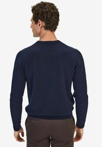 Marineblauwe gebreide trui met lange mouwen, geribbelde kraag en boorden. Heeft een gestructureerde stof en een rechte pasvorm.